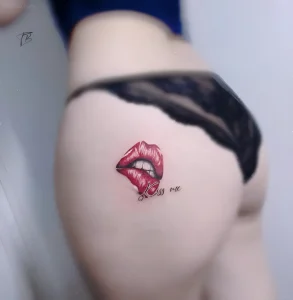 Татуировка красных губ с надписью 'Kiss me' на ягодице