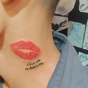 Татуировка в виде красного поцелуя с надписью "Love me or leave me" на шее, выполненная в графическом стиле