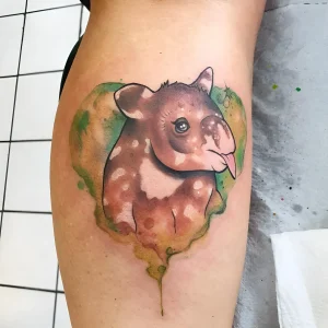 Фото татуировки тапира в стиле акварель с зеленым фоном, выполненной на руке.