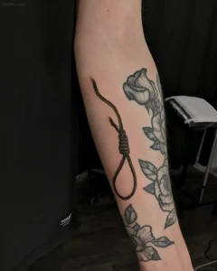 Татуировка петли с узлом и розы в графическом стиле на предплечье