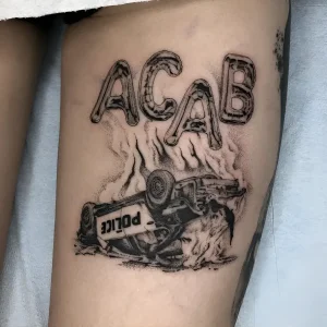 Татуировка ACAB с перевернутой полицейской машиной в огне, выполненная в черно-серой гамме.