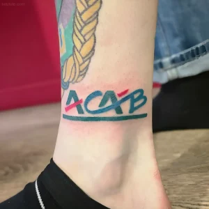 Татуировка ACAB на лодыжке, выполненная в современном стиле с яркими цветами
