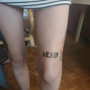 Татуировка ACAB на бедре девушки