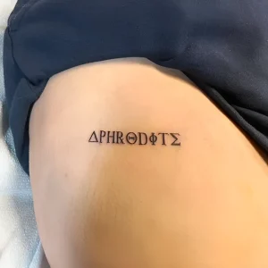 Миниатюрная татуировка с греческим словом "Афродита" на боку