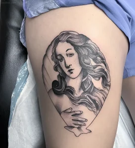 Татуировка в стиле гравюры, изображающая Венеру (Афродиту) внутри раковины. Детальная прорисовка лица, волос и рук.