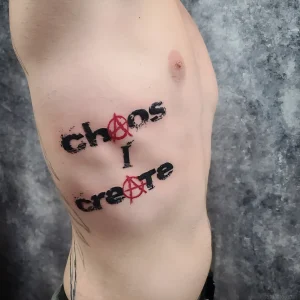 Татуировка надписи «Chaos I Create» с символом анархии на боку