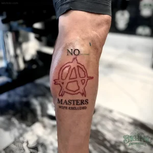 Татуировка символа анархии с надписью «NO MASTERS» на ноге