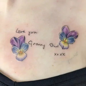 Татуировка анютины глазки с надписью "Love you Granny Owl" на груди