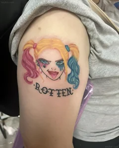 Татуировка Арлекин с яркими волосами, безумным взглядом и надписью "ROTTEN" на плече