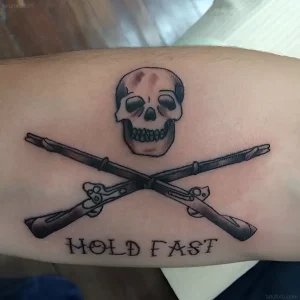 Татуировка череп и скрещенные мушкеты с надписью "Hold Fast"