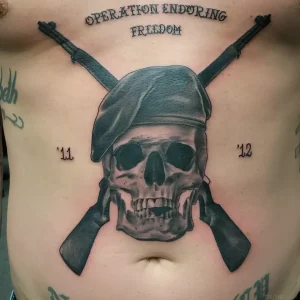Татуировка черепа в берете с перекрещенными автоматами и надписью 'Operation Enduring Freedom'