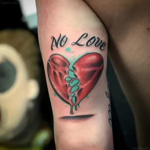 Татуировка разбитого сердца с надписью "No Love" и бирюзовыми брызгами