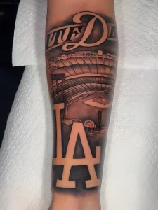Татуировка спортивного стадиона с надписью "LA" и "DODGERS" на предплечье