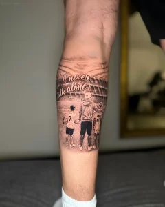 Татуировка спортивный стадион с тремя фигурами людей и надписью "You'll never walk alone"
