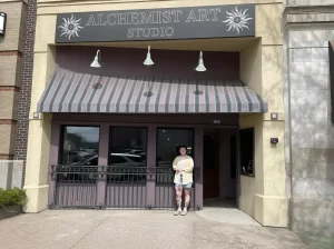 Grace DeVrieze stands in front of the entrance to Alchemist Art Studio tattoo shop at 1623 in downtown Rock Island, Illinois.