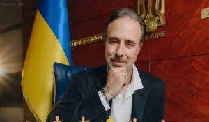Итальянский тренер Андреа Мальдера в кабинете УАФ, на фоне украинский флаг и герб, в руке держит микрофон