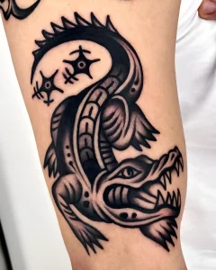 Детальная черно-белая татуировка агрессивного крокодила с открытой пастью и звездочками в стиле American Traditional на руке