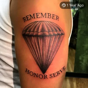 Детальное фото реалистичной татуировки парашюта с текстом Remember Honor Serve на бедре мужчины