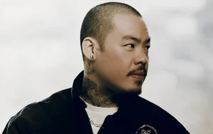 Портрет знаменитого тату-мастера Dr. Woo в профиль, демонстрирующий его характерные татуировки на шее и ухе.