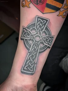Чёрно-белая татуировка кельтского креста с узорами в стиле Blackwork на предплечье.