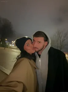 Селфи Майи Джаммы и Рубена Диаша в ночном городском пейзаже, где пара позирует в зимней одежде