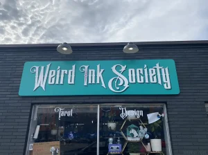 Вывеска тату-салона 'Weird Ink Society' на фоне пасмурного неба