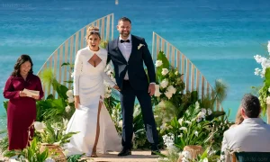 Gia из MAFS Australia и Скотт стоят на фоне океана во время свадебной церемонии, невеста взволнована, жених улыбается.