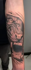 Detailed tiger tattoo on the arm, executed in hyperrealism style with depth and volume effect.