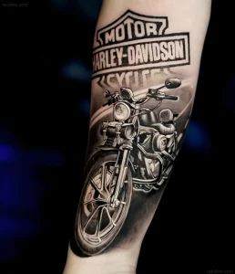 Черно-белая татуировка с классическим логотипом Harley-Davidson и детализированным мотоциклом на руке