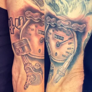 Детальная фотография реалистичной татуировки на мужском предплечье, изображающей автомобильный тахометр с датой 01.10.13, поршень двигателя, шатун и цепь.