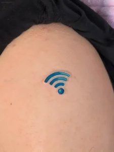 Крупный план свежей татуировки в виде синего логотипа Wi-Fi на бедре человека, выполненной в минималистичном стиле