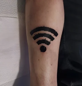 Черно-белая татуировка в виде значка Wi-Fi на коже предплечья, выполненная в стиле минимализм с четкими линиями и кругом в основании