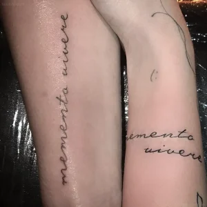 Детальное описание татуировки с надписью 'momenta vivere' на коже, символизирующей философию жизни и стиль.