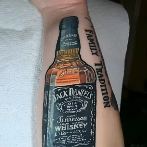 реалистичная татуировка бутылки виски Jack Daniel's с надписью Family Tradition на руке