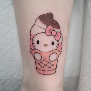 татуировка на ноге с изображением персонажа Hello Kitty, стилизованного под мягкое мороженое в конусе, розовая гамма