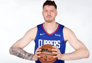 Исаия Хартейнштейн в синей форме Clippers держит баскетбольный мяч, демонстрируя реалистичную татуировку на правой руке