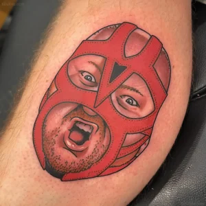 татуировка luchador с лицом человека под красной маской на руке