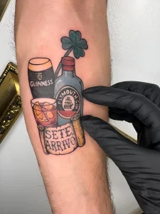 татуировка на предплечье с изображением бутылки Plymouth Gin, стакана Guinness, бокала с коктейлем и надписью SETE ARRIVO