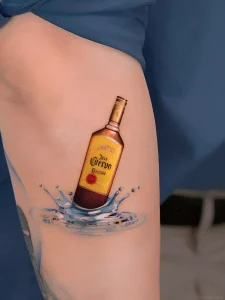 татуировка на бедре с изображением бутылки текилы Jose Cuervo, выходящей из воды с брызгами