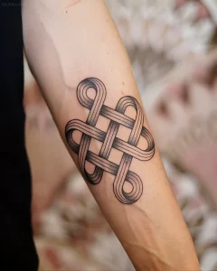 Черно-серая татуировка в стиле шотландский узел (Scottish knot) на внутренней стороне предплечья человека, выполненная с использованием градиентного дотворка и четких контуров.