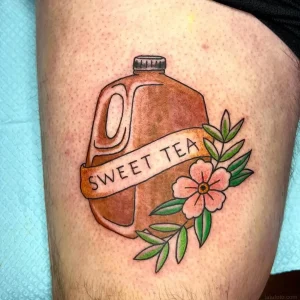 Татуировка на плече с изображением коричневого кувшина с этикеткой SWEET TEA, лентой и розовым цветком