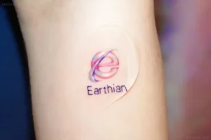 Татуировка на предплечье с красным и синим логотипом Earthian, символизирующая интернет-тематику ко дню рождения Интернета 17 мая