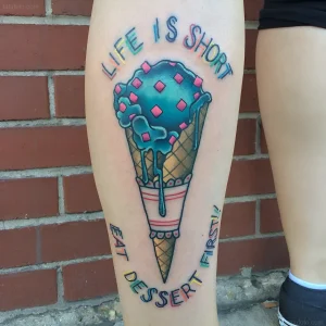 Татуировка с голубым мороженым в рожке и надписью Life Is Short Eat Dessert First на бедре