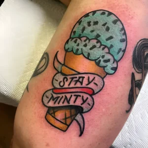 Татуировка с рисунком мороженого в стиле нео-традишн, надпись Stay Minty на ленте, бирюзовый цвет, тату на руке