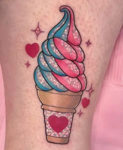 Татуировка на ноге с изображением мягкого мороженого (soft serve) в стаканчике. Десерт выполнен в розовом и голубом цветах с эффектом глиттера, в окружении сердец и звезд.