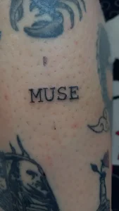 Крупный план татуировки с текстом MUSE на коже, выполненной в стиле минимализма, в контексте праздника 17 июня
