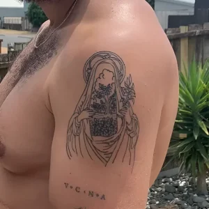 татуировка в стиле neo-traditional на плече мужчины, изображающая женскую фигуру с венцом из глобуса и буквой V.C.N.A.
