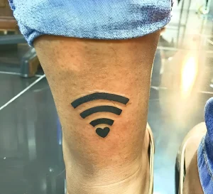 Черная минималистичная татуировка с символом Wi-Fi и сердцем внизу на голени человека в джинсах