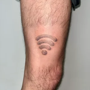 Черно-белая татуировка в виде символа Wi-Fi, выполненная техникой дотворк (точечная техника) на волосатом предплечье мужчины. Четкие изогнутые линии и круг, составленные из мелких точек, создают узнаваемый логотип беспроводной сети.