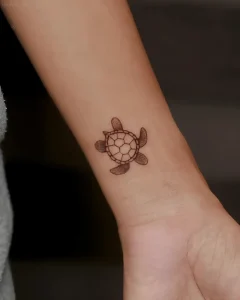 Миниатюрная татуировка морской черепахи на запястье руки в стиле dotwork